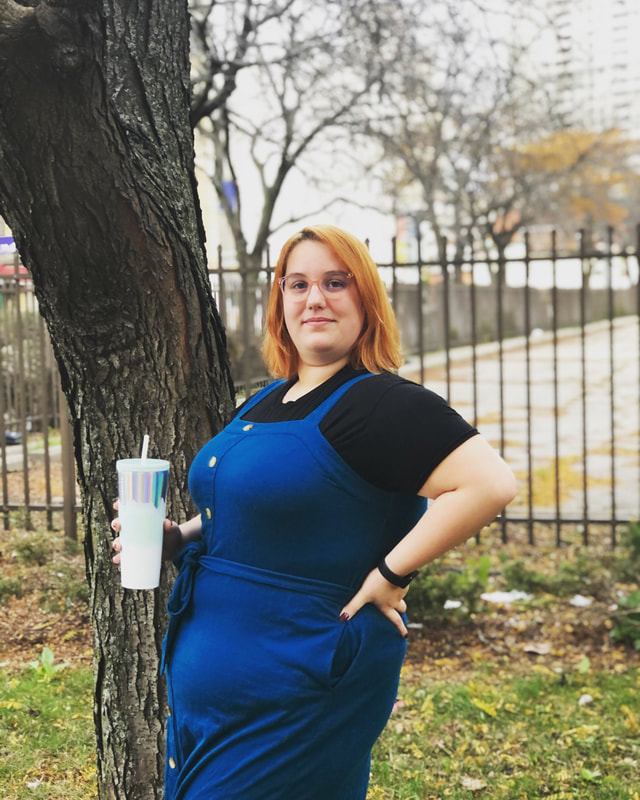 Photo of Brandi outside in Detroit, wearing a blue dress and holding a blue cup.